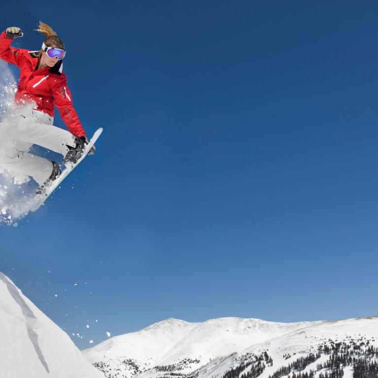 Jente kjører snowboard på fjelltopp Jente kjører snowboard på fjelltopp
